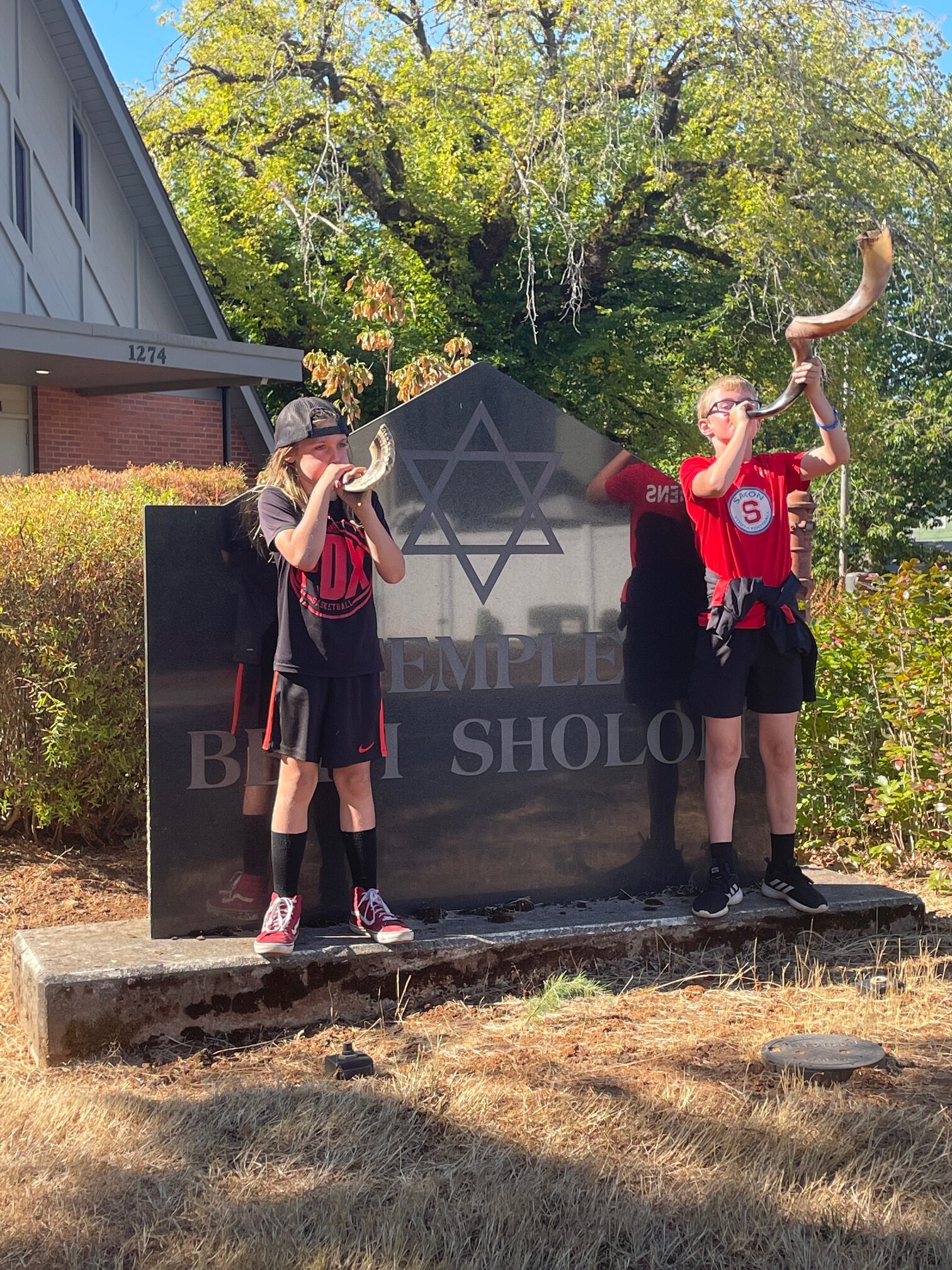 Kids blowing shofar in front of TBS sign