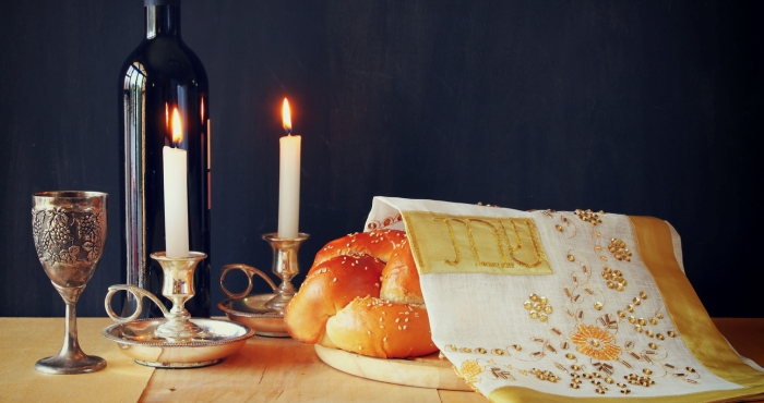Shabbat candles, challah, kiddush cup, and wine bottle