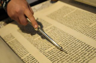 Hand holding yad pointing at Torah
